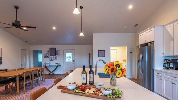 A spacious kitchen with a central island, white cabinetry, and a modern ceiling fan. - Blue Moon Escape (Paso Robles)