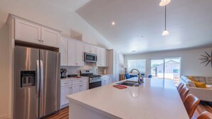 A modern kitchen with stainless steel appliances, white cabinetry, and a large island. - Blue Moon Escape (Paso Robles)