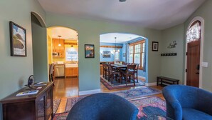 A spacious living room with a large blue sofa, a glass coffee table, and a dining area with wooden furniture. - Crafty Oak House (Paso Robles)