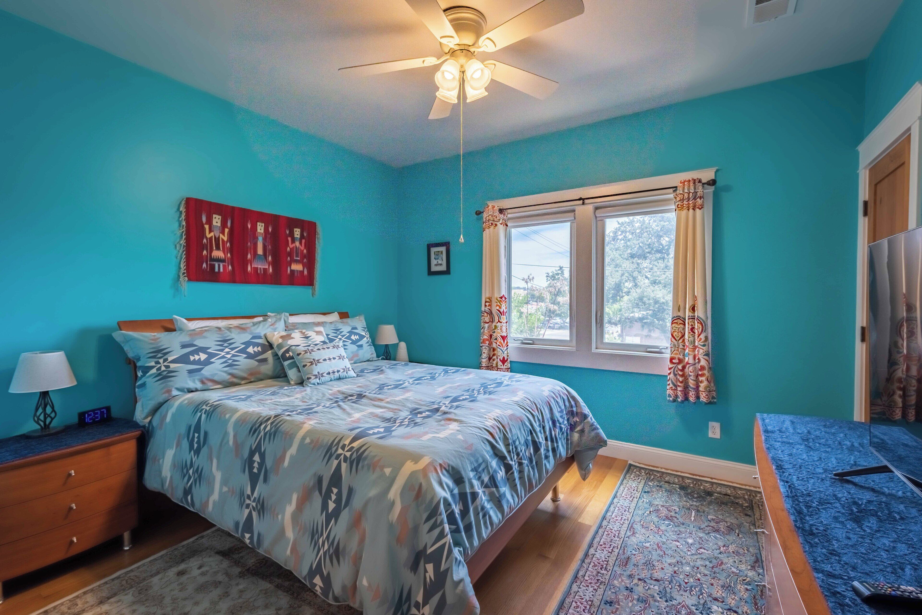 A bedroom with a bed, nightstand, lamp, and a ceiling fan.