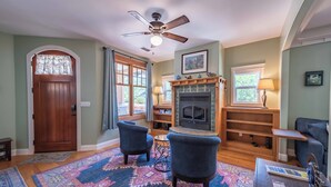 A cozy living room with a fireplace, two armchairs, a coffee table, and a patterned rug. - Crafty Oak House (Paso Robles)