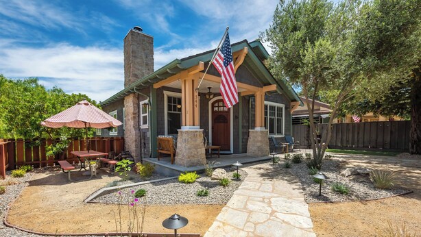 A house with a stone patio, outdoor seating, and an American flag. - Crafty Oak House (Paso Robles)