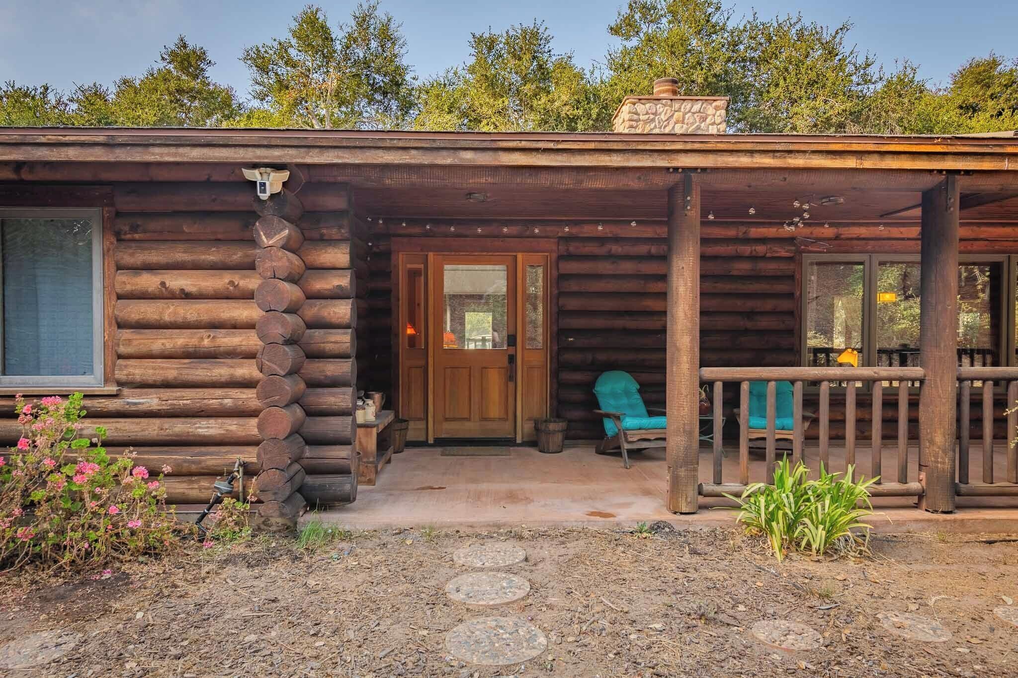 A log cabin with a porch, a wooden door, and a chair outside.