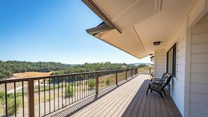 Une terrasse en bois avec une rambarde, une table et deux chaises.