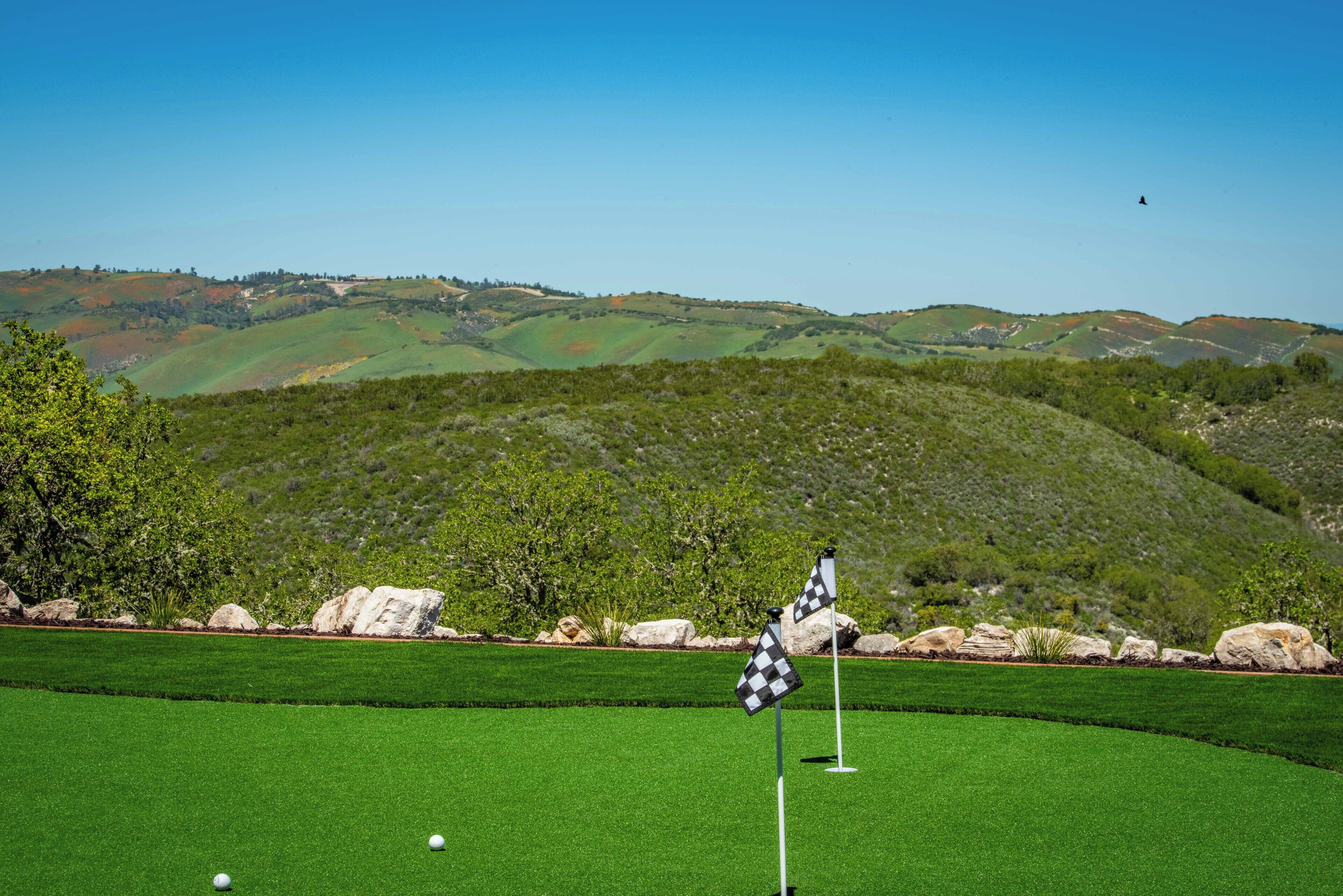 Un terrain de golf avec un mât de drapeau, un drapeau et un ciel dégagé.
