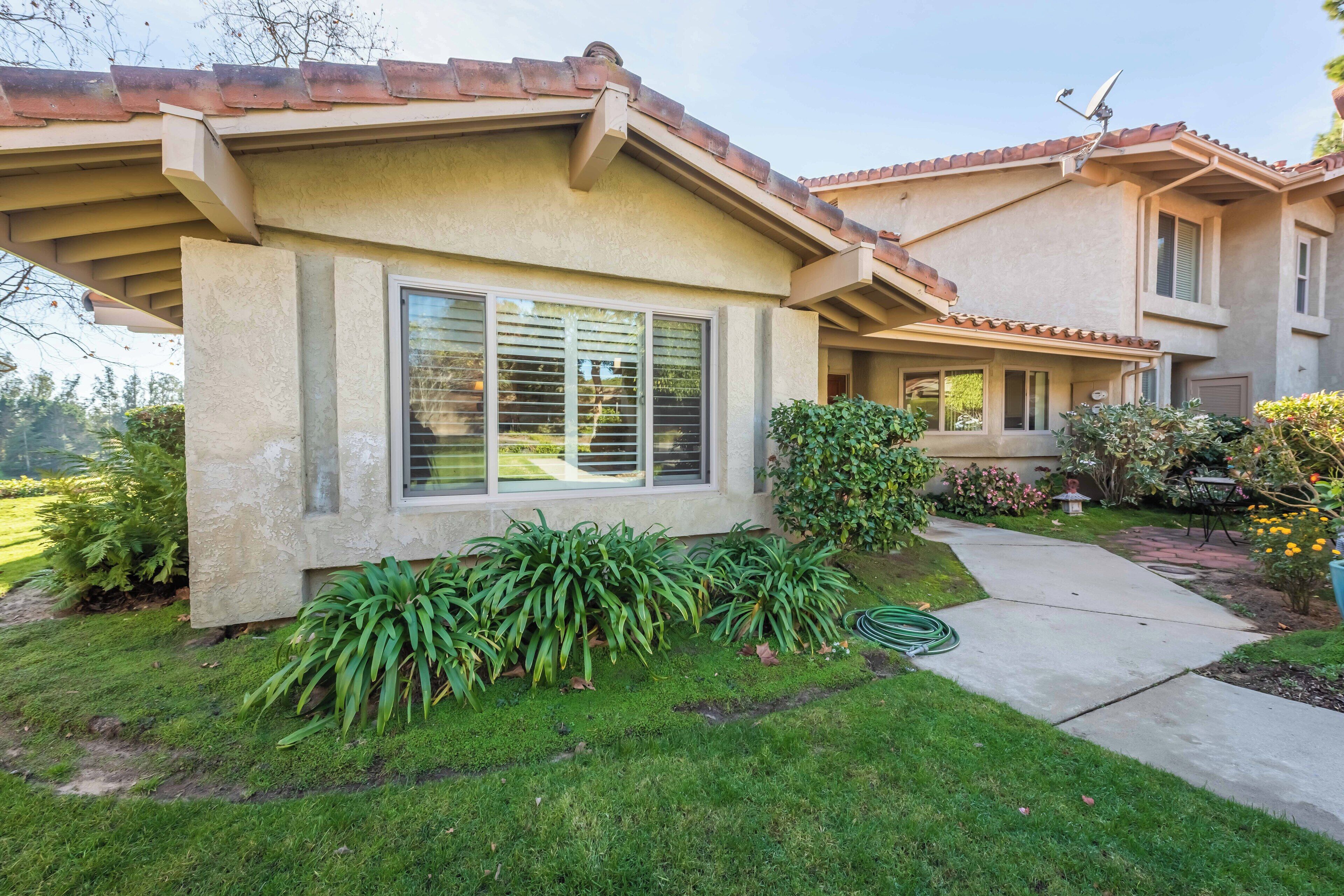 A two-story house with a beige exterior, large windows, and a tiled roof.