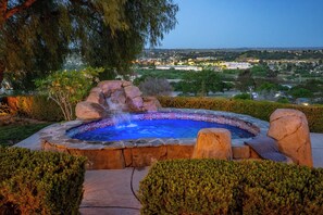 A hot tub with a waterfall feature surrounded by well-maintained hedges and a view of a residential area. - Paso Palacio (Paso Robles)