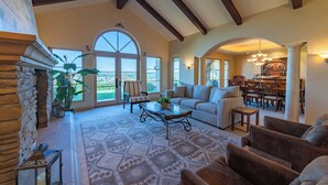 A spacious living room with a fireplace, large windows, and a dining area. - Paso Palacio (Paso Robles)
