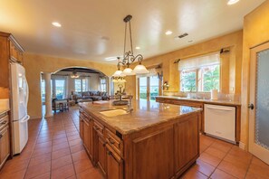 A spacious kitchen with wooden cabinets, a large island, and a built-in dishwasher. - Paso Palacio (Paso Robles)