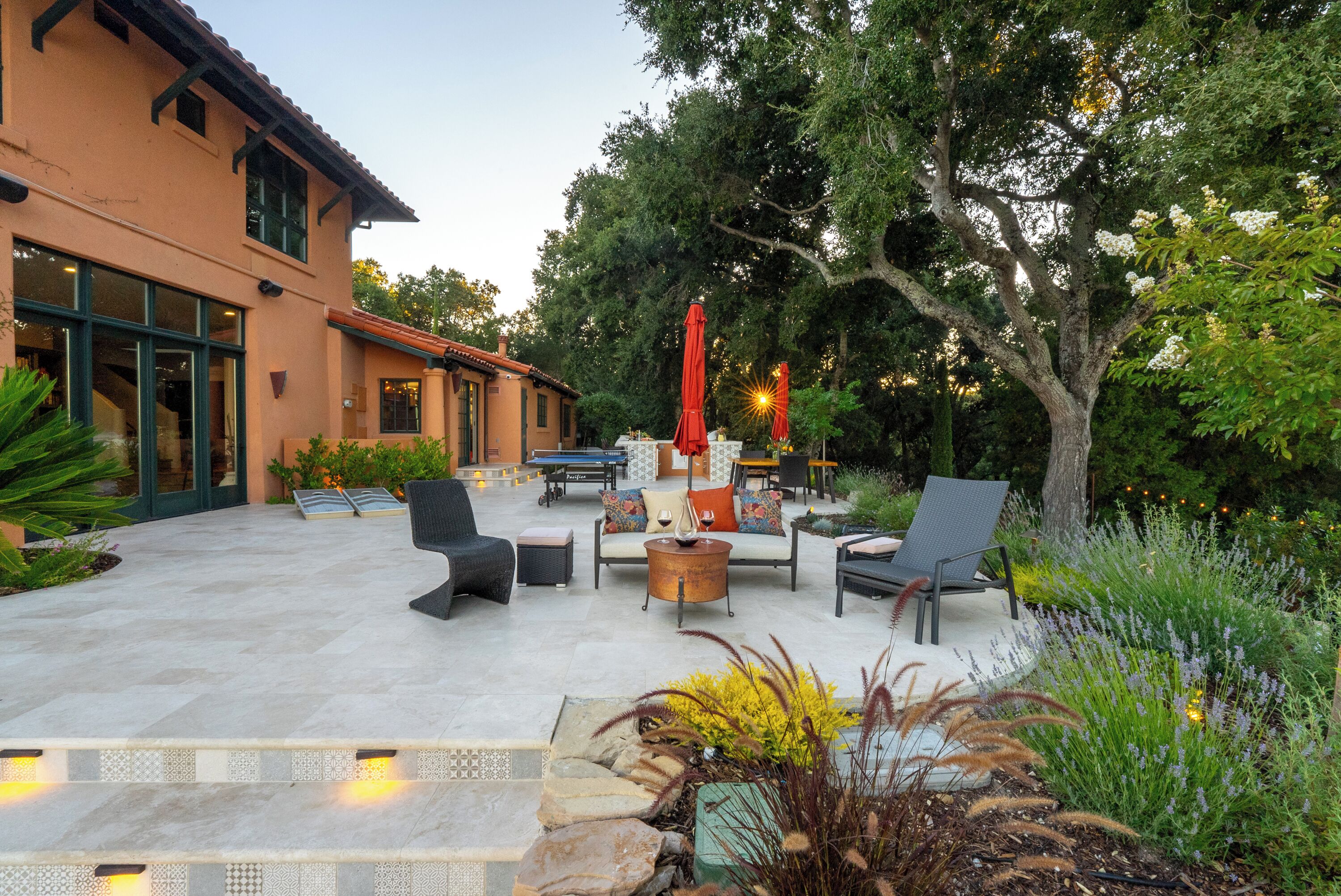 Un patio exterior con asientos, una chimenea y un árbol grande.
