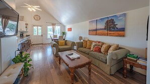 A spacious living area with a sofa, coffee table, and a dining area with a kitchen in the background. - Red Barn Loft (Templeton)