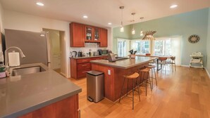 Une cuisine moderne avec des meubles en bois, un réfrigérateur en acier inoxydable et un îlot central doté de tabourets.