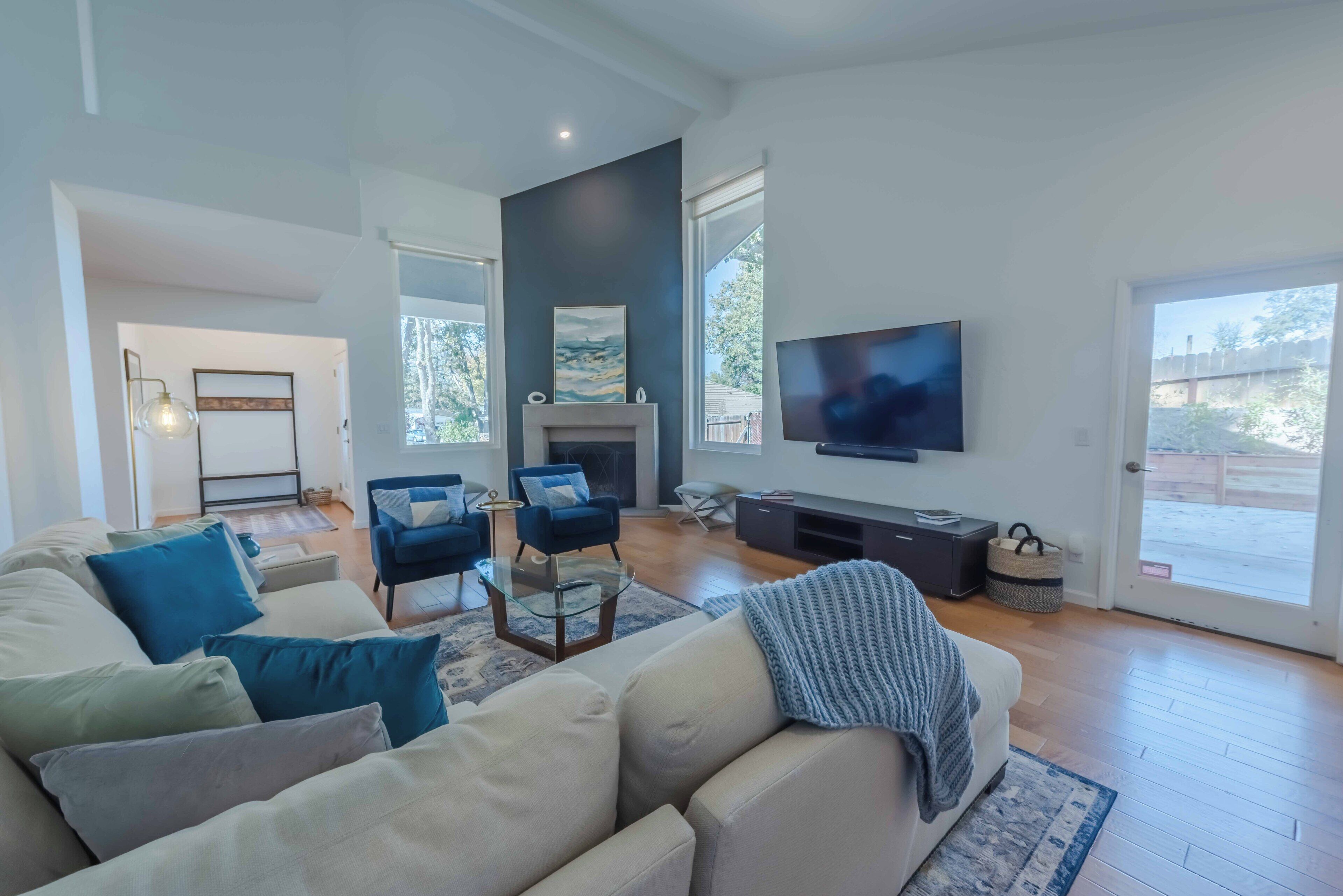 Un salon moderne doté d’un grand canapé, d’une cheminée, d’un téléviseur et offrant une vue sur l’extérieur.