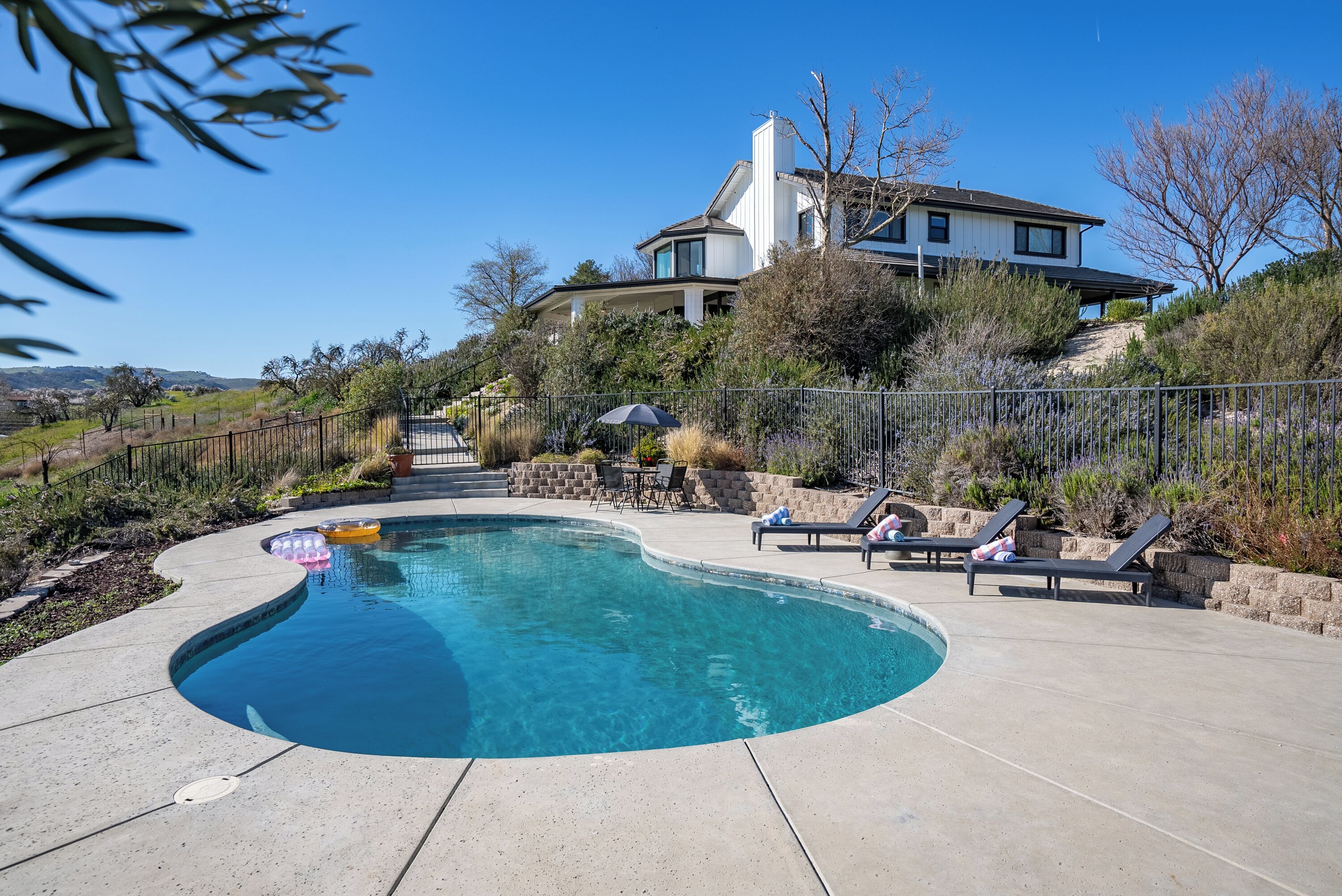 A swimming pool with lounge chairs and a view of a house.