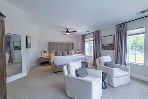 A bedroom with a large bed, two armchairs, a ceiling fan, and a large window with curtains. - Hilltop Oasis (Templeton)