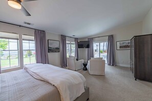 A hotel room with a large bed, a flat-screen TV, a seating area with chairs, and a wardrobe. - Hilltop Oasis (Templeton)