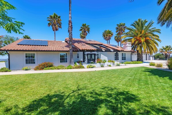A modern house with a tiled roof, solar panels, and a well-maintained lawn.