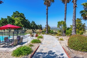 A patio with a pool, outdoor furniture, and a red umbrella. - Hilltop Oasis (Templeton)