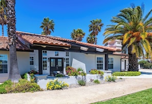 A two-story house with a tiled roof, a front porch, and a well-maintained garden with various plants and flowers.