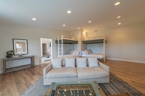 A modern living room with a sofa, a foosball table, and a bunk bed. - Hilltop Oasis (Templeton)