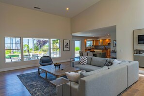 A spacious living room with a large sofa, a coffee table, and a view of the outdoor patio.