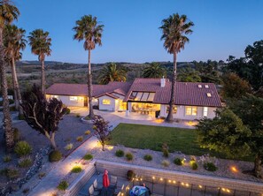 A two-story house with a patio, surrounded by palm trees and a landscaped garden. - Hilltop Oasis (Templeton)
