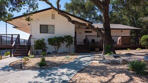 A single-story house with a covered porch, a stone pathway, and a small garden with shrubs and a cactus. - Heartview Cottage (Templeton)