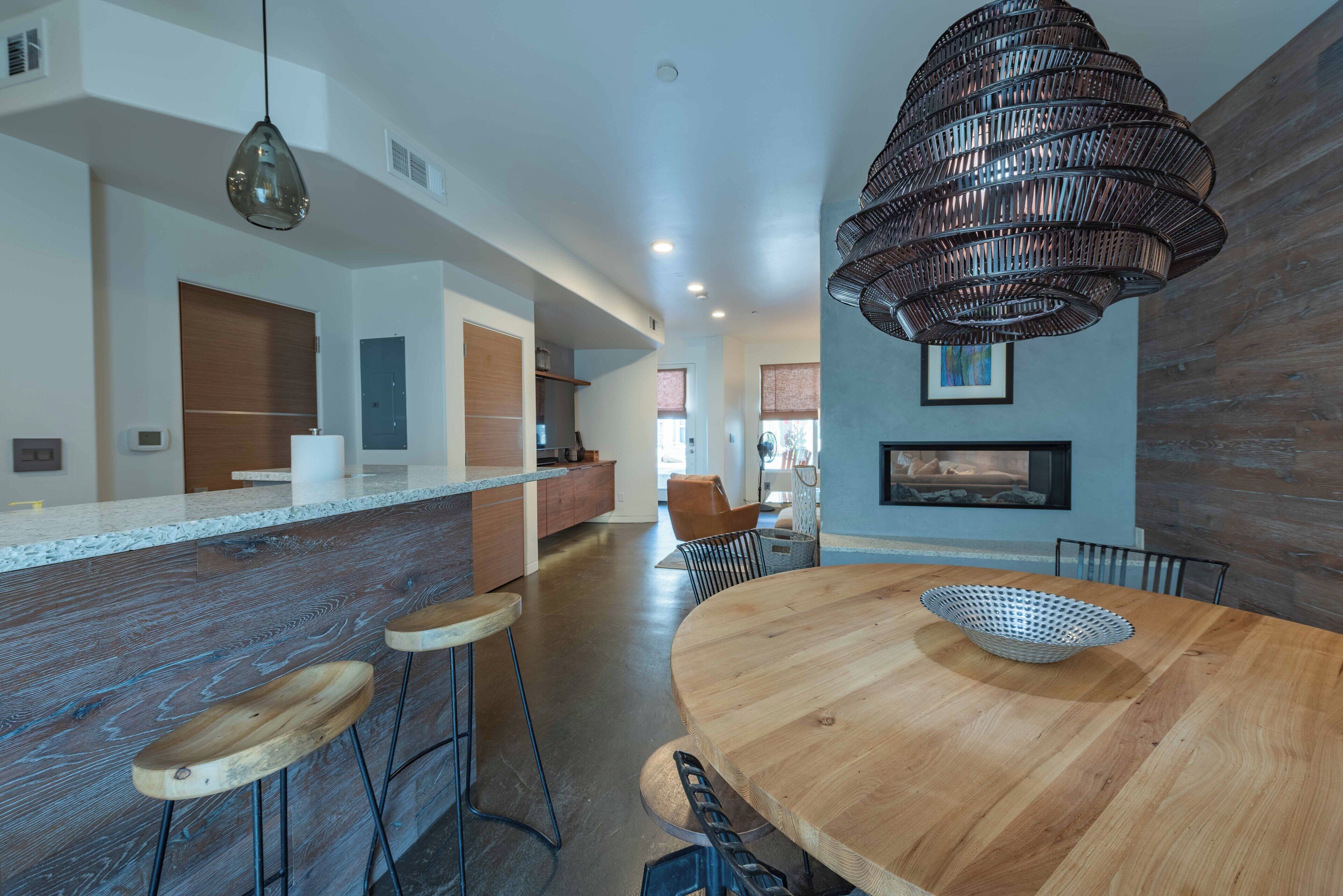 Una cocina moderna con encimera de madera, taburetes de bar y una lámpara colgante.