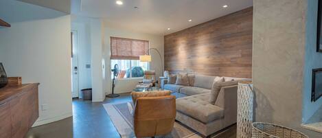 Una sala de estar moderna con un amplio sofá modular, una mesa de centro y una pared de acento de madera.