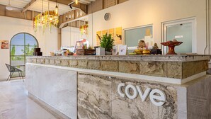 A reception area with a marble counter, hanging lights, and a clock on the wall. - Cove Kisah Residence (Munggu)