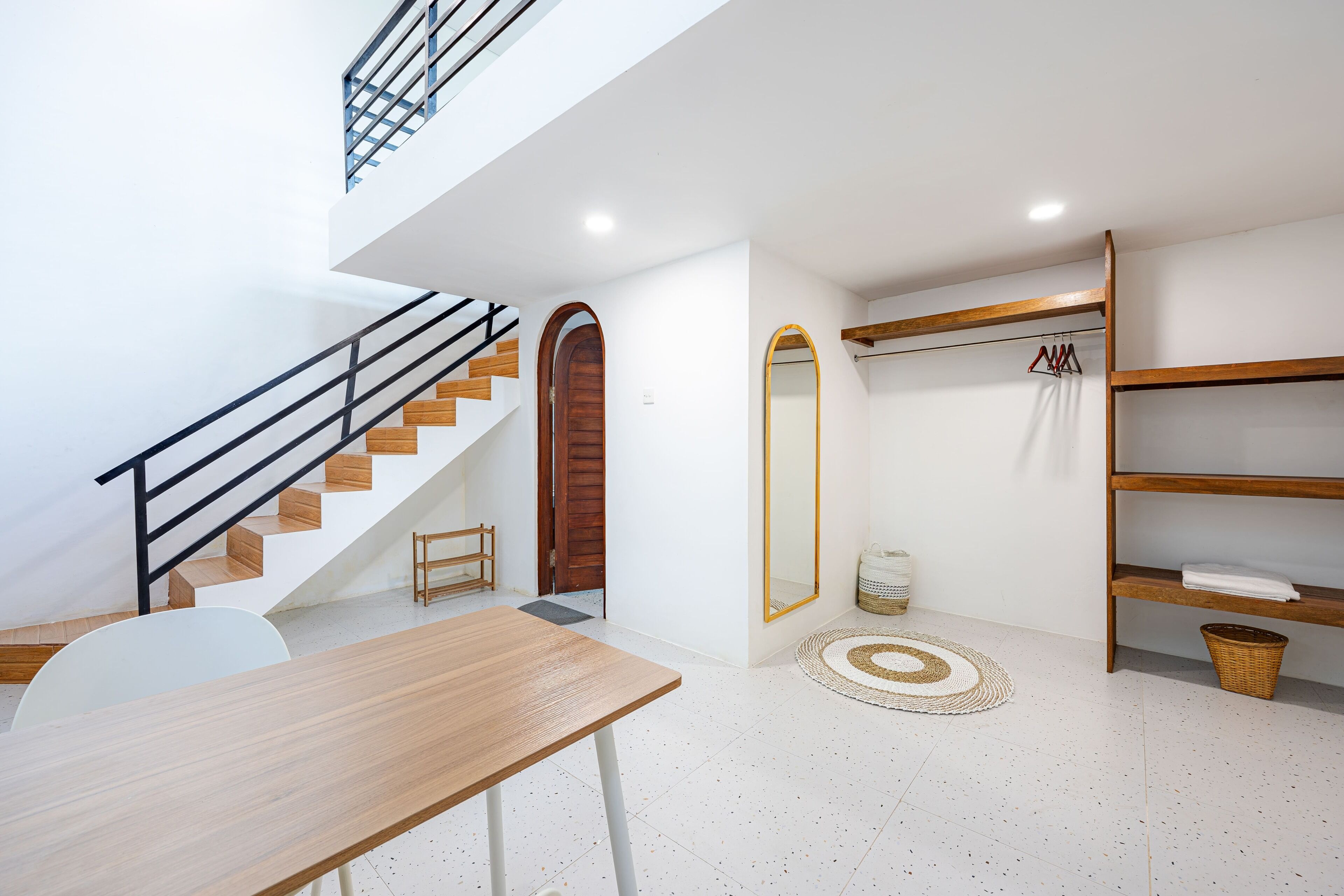 Un interno moderno con una scala, un tavolo in legno, uno specchio e uno scaffale con asciugamani.