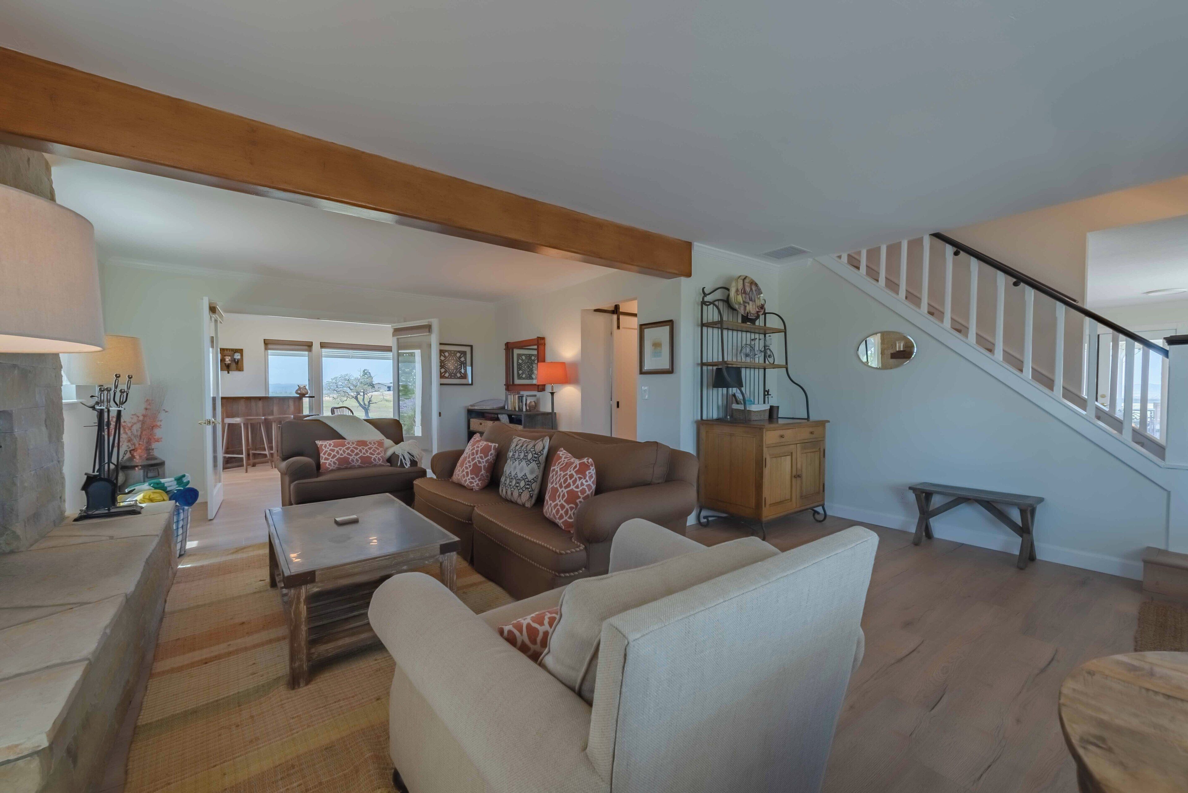 Ein geräumiges Wohnzimmer mit einer Holztreppe, einer Sofagarnitur, einem Couchtisch und einem Kamin.