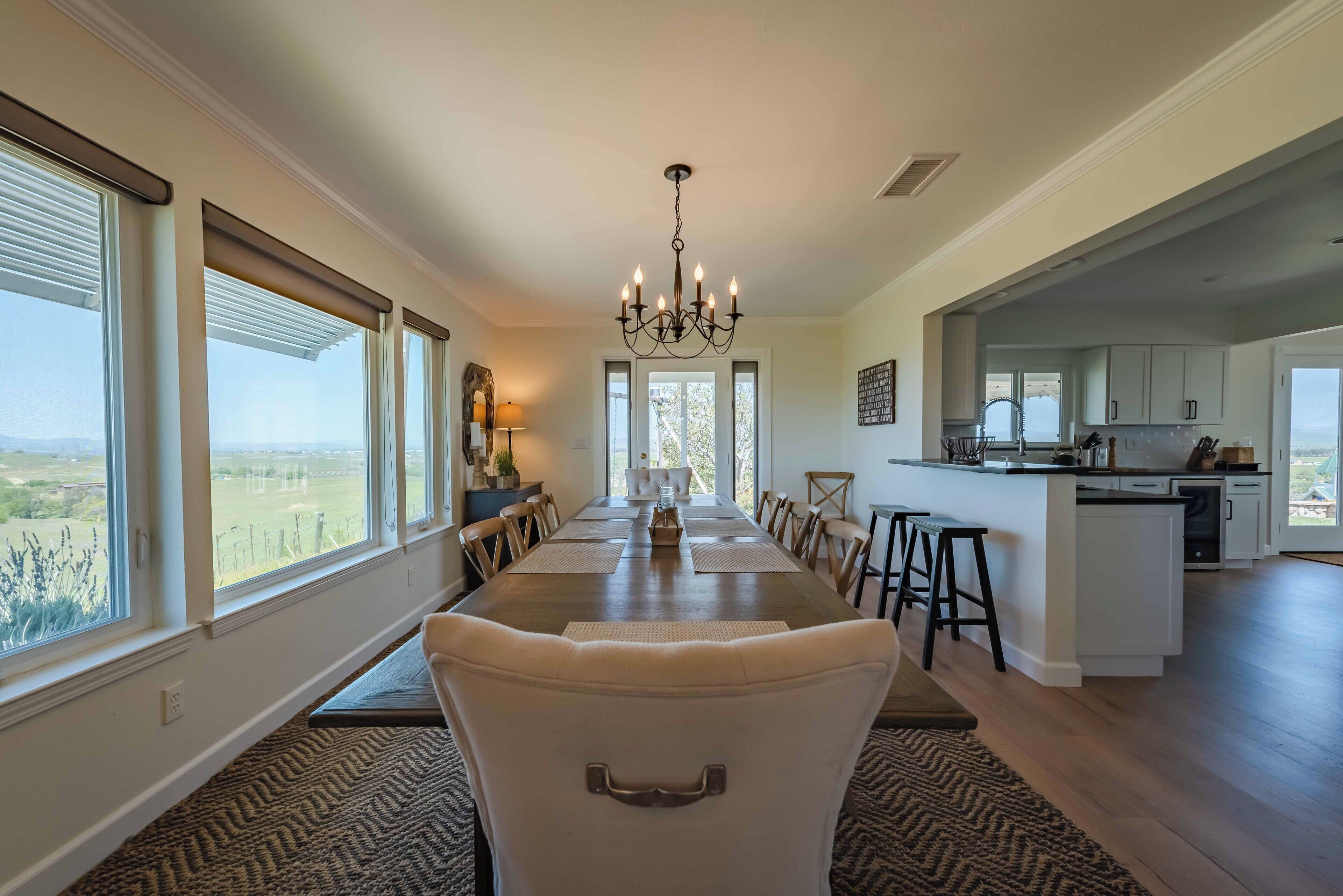 Un comedor amplio con una larga mesa, ventanas grandes y vistas al exterior.