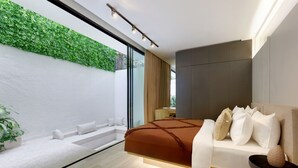 Une chambre moderne avec un grand lit, un canapé blanc, une petite table et un mur vert.