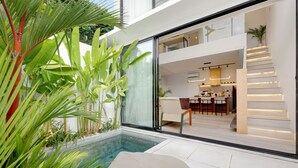 Une maison moderne dotée d’une piscine à débordement, d’un espace repas et d’un escalier menant à un niveau supérieur.