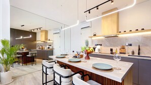 Une cuisine moderne dotée d’un îlot central, de tabourets de bar et d’un coin salon.