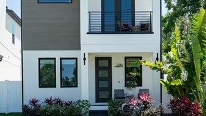 Ein modernes, zweistöckiges Haus mit Balkon, Eingangstür und Briefkasten.