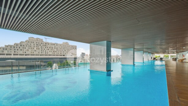 An indoor swimming pool with a modern ceiling design and a view of a cityscape in the background. - Brenna by Kozystay - Menteng (Jakarta)