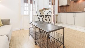 Cozinha moderna com armários brancos, exaustor de aço inoxidável e mesa dobrável com base de arame.