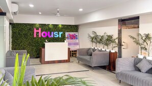 A reception area with a green wall, a reception desk, and two sofas.