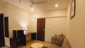 A compact living space with a sofa, a small table, a TV, and a ceiling fan.