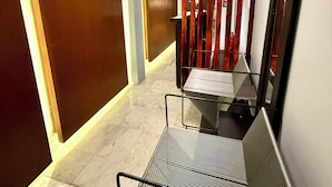 A modern hallway with a metal bench, wooden doors, and a ceiling light. - RMS Suites - Zona Rosa (Mexico City)