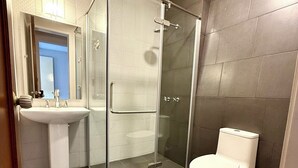 A modern bathroom with a glass-enclosed shower, a white sink, and a toilet. - RMS Suites - Zona Rosa (Mexico City)