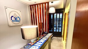 A reception desk with a "Bienvenidos" sign, a lamp, and a "Roomies" logo on the wall. - RMS Suites - Zona Rosa (Mexico City)