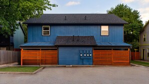 A two-story blue house with a garage, a small window on the upper floor, and a metal roof. - Rare 2BR in Prime Location (Austin)
