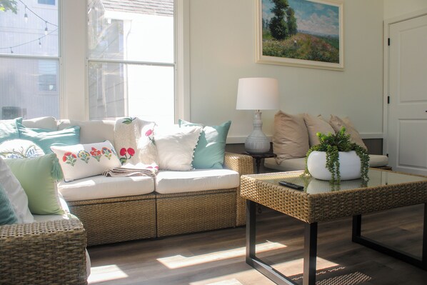 A cozy living room with a wicker sofa, a glass coffee table, and a painting on the wall. - Alpaca Grand Vacation Rental (Sister Bay)