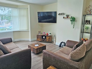 Una sala de estar con sofá, mesa de centro, televisor y elementos decorativos.