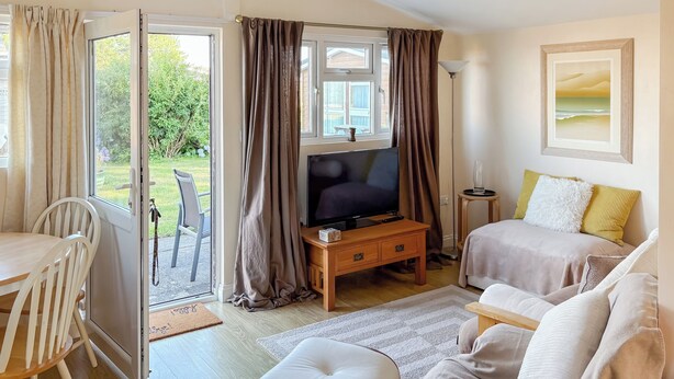 Una habitación acogedora con televisor, cama, mesa de comedor y vistas al exterior.