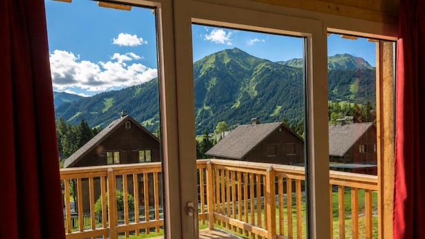 A wooden deck with a view of mountain houses and a clear sky.