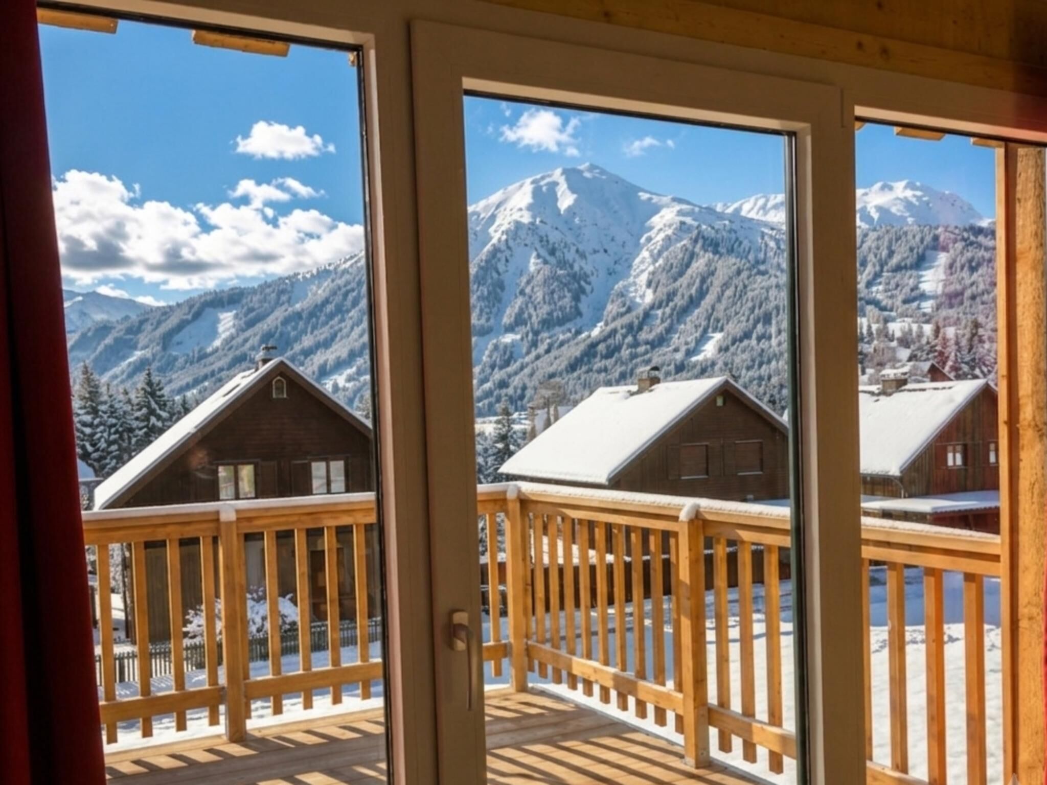 A wooden balcony with a view of snow-covered mountains and cabins.